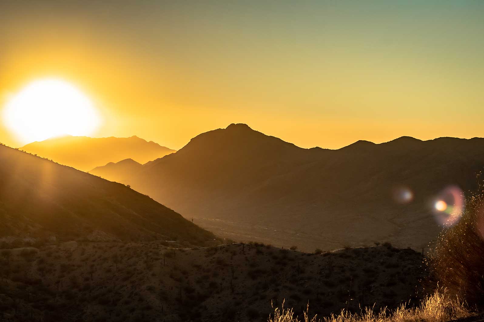 Sun rising over a desert mountain range